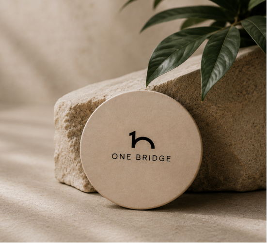 OneBridge tap product resting against a stone with a plant